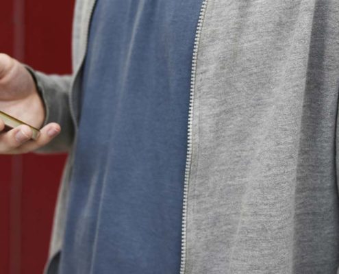 Mann mit Smartphone vor PAKETIN-Schließfach